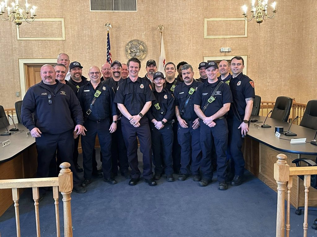 Firefighter Andrew Clark standing with members of the Granite City Fire Department after his swearing‑in ceremony.